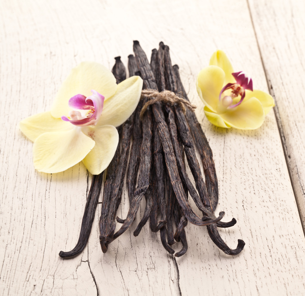 Vanilla sticks with a flower on a white wooden table.